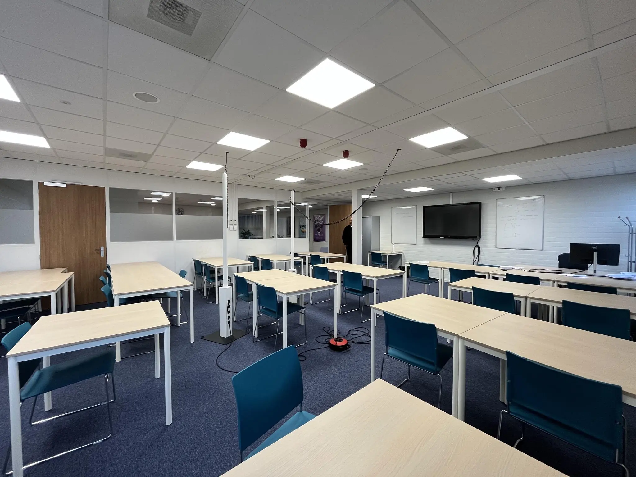 Modern klaslokaal aan de Niels Bohrweg met meerdere bureaus, stoelen, een digibord en whiteboards.